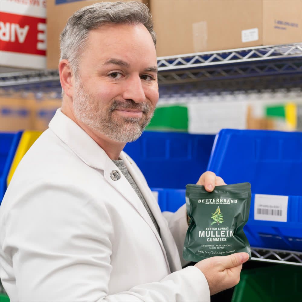 Chris Jackson, PharmD, on the Betterbrand fulfilment floor holding a bag of BetterLungs Mullein Gummies